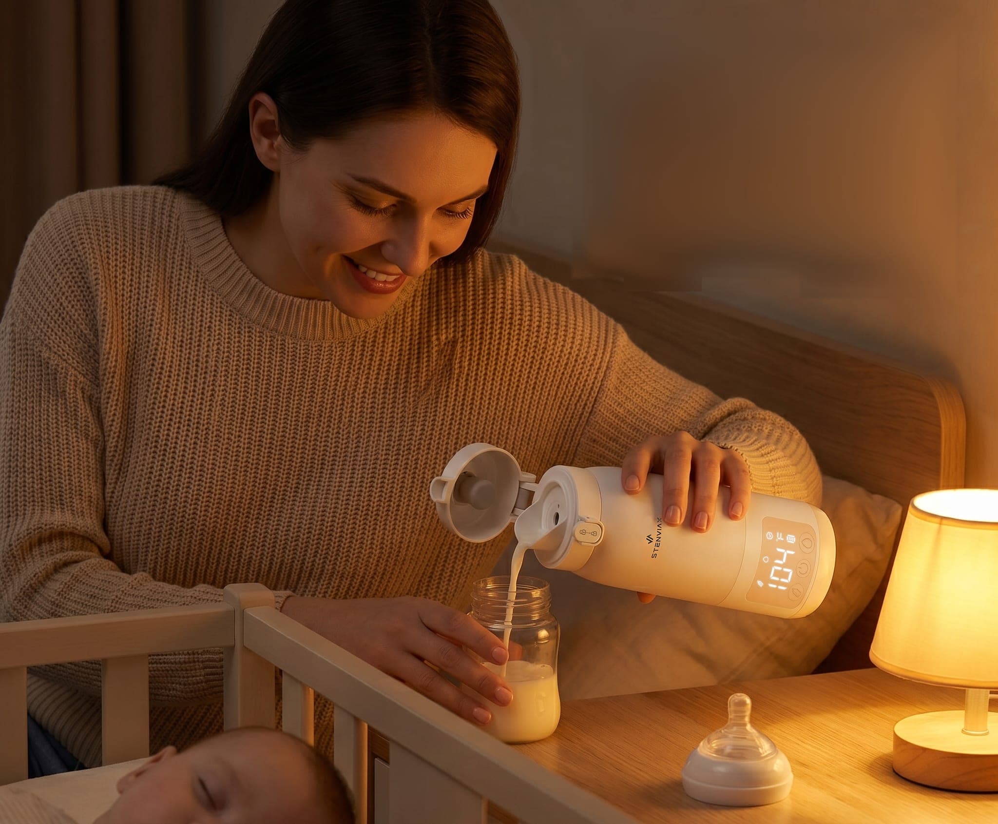 A smiling mother pouring warm milk from a Luxe White Stenviax warmer into a bottle beside her sleeping baby's crib, a bedside lamp glowing