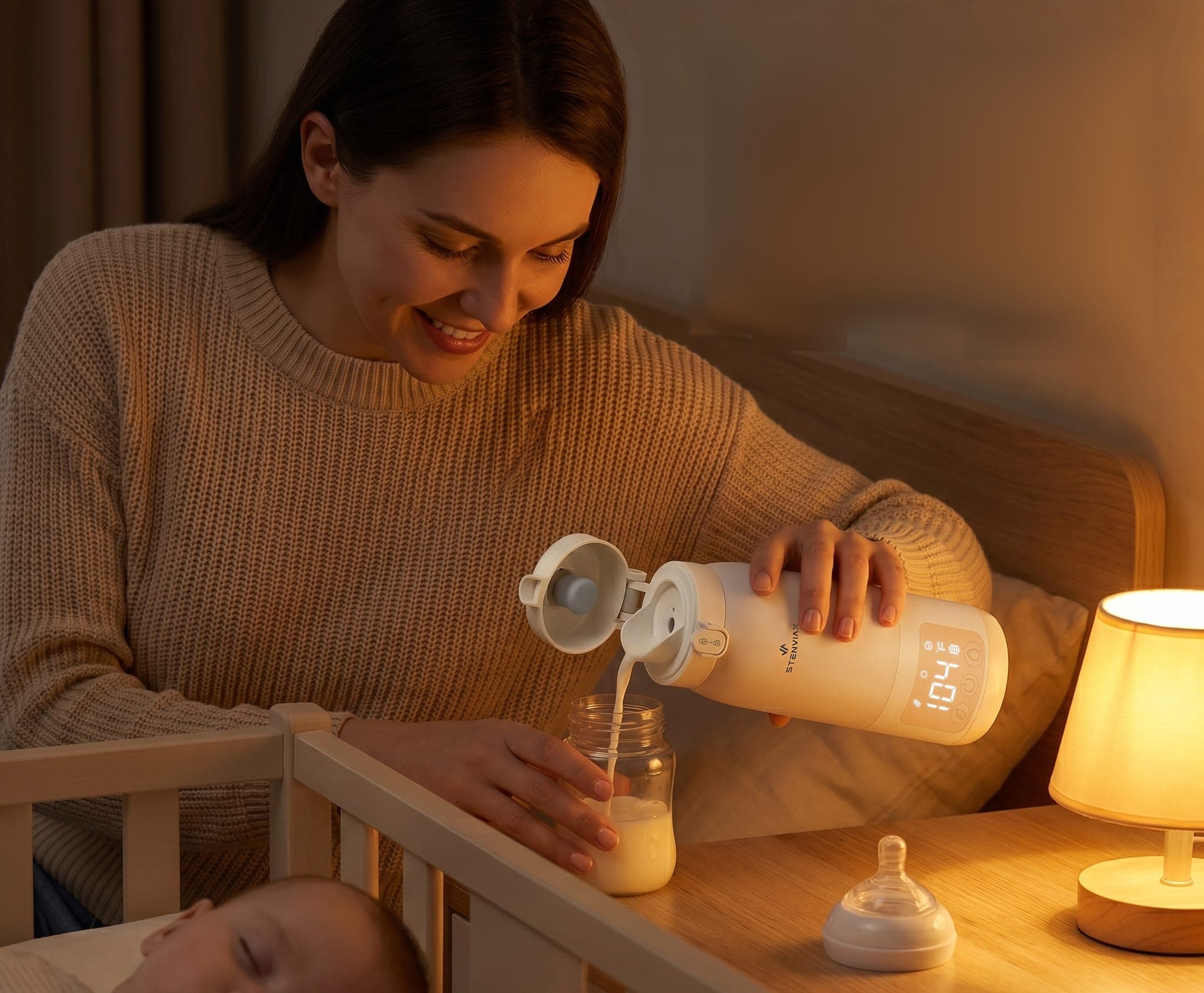A mother smiling as she pours a warmed bottle at the bedside while the baby sleeps